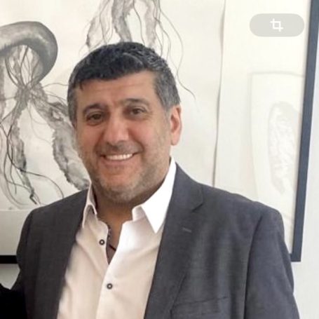 CEO für geschäftliche Anliegen Mann in Anzug lächelt vor zeitgenössischer Kunst und einem neutralen Hintergrund.